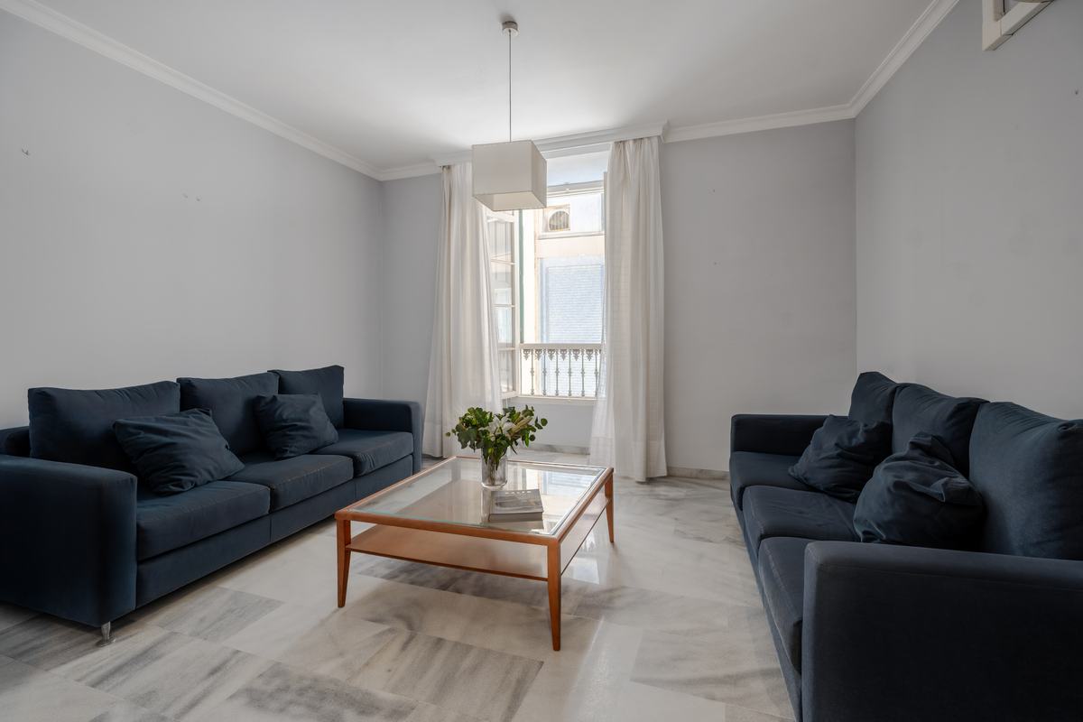Salón con dos sofás azules, mesa de centro de madera y luz de ventanal